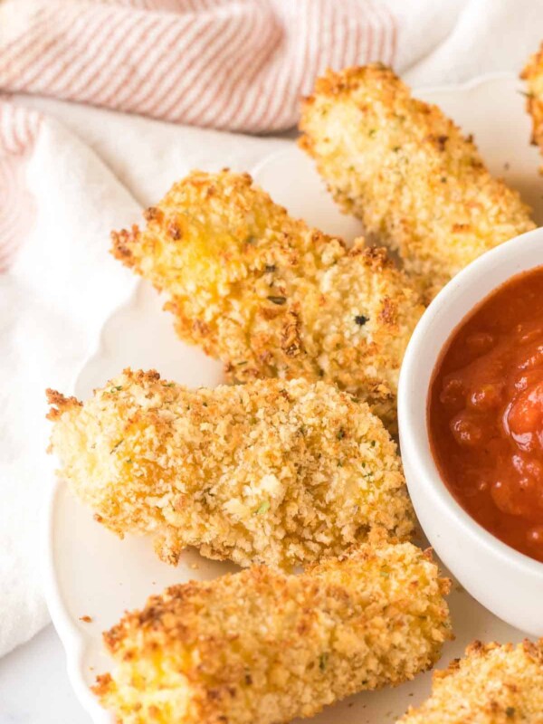 close up circular plate with a ring of air fryer mozzarella sticks around marinara sauce