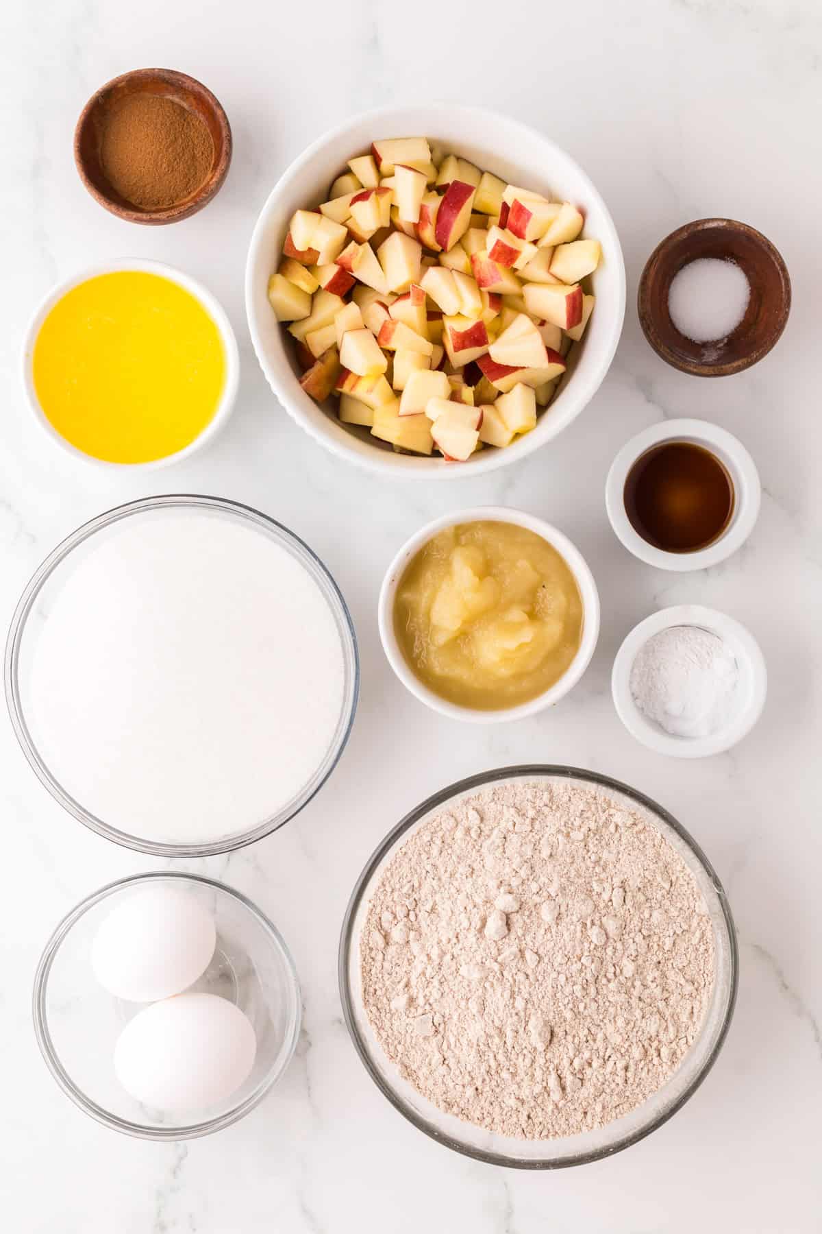 portion bowls each with raw ingredients to make apple cake.