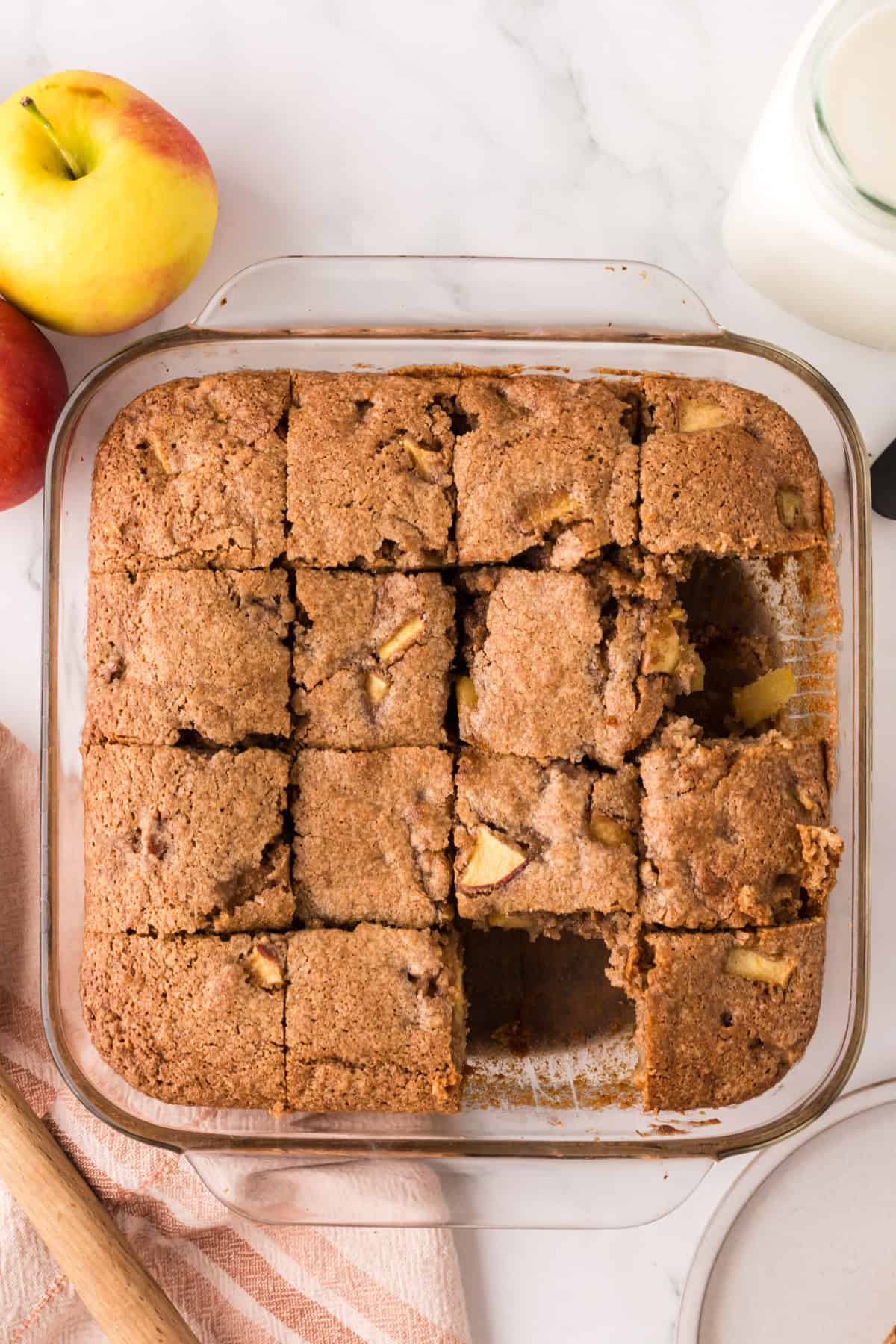 apple cake in a clear pan sliced into squares.