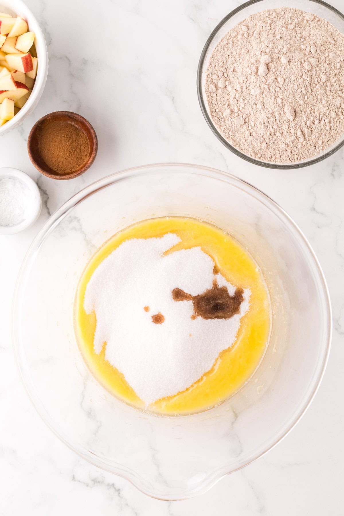 apple cake ingredients in a clear mixing bowl.