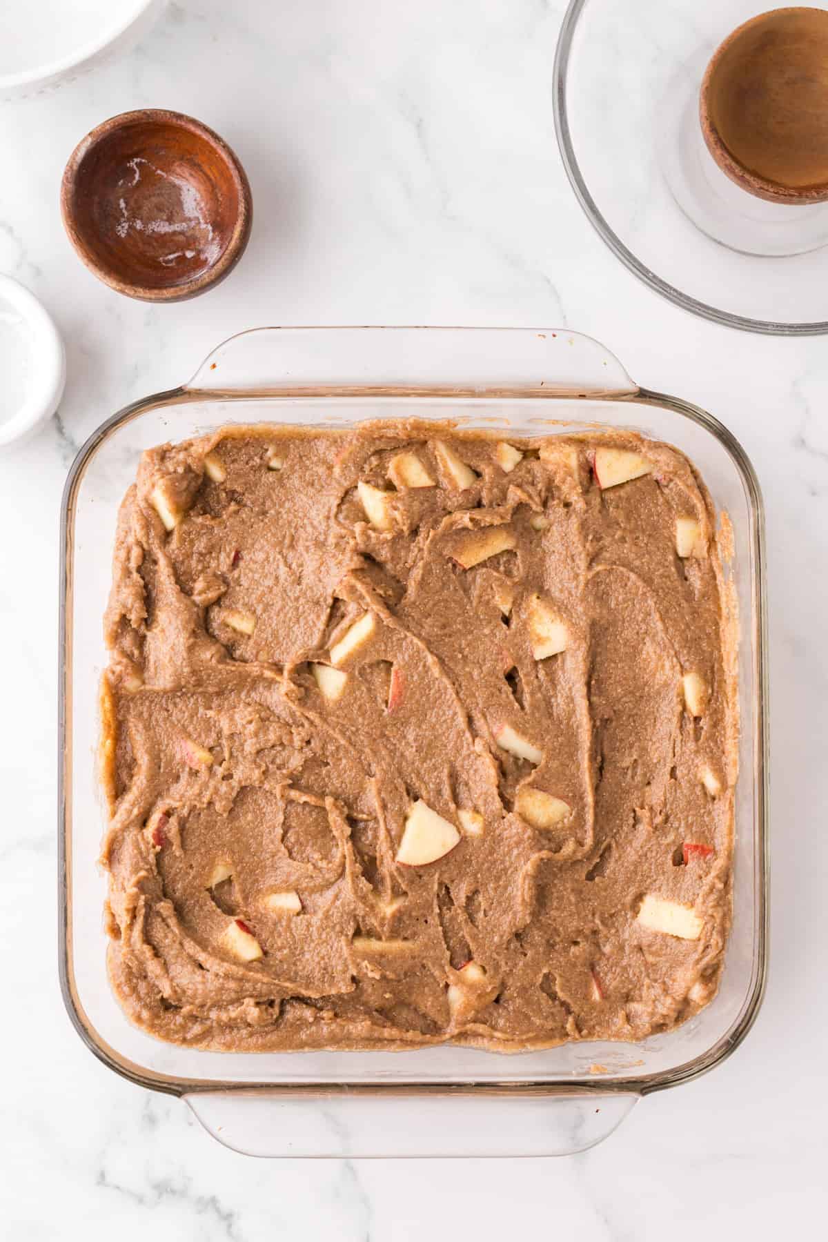 whole apple cake recipe in a glass pan before being baked.