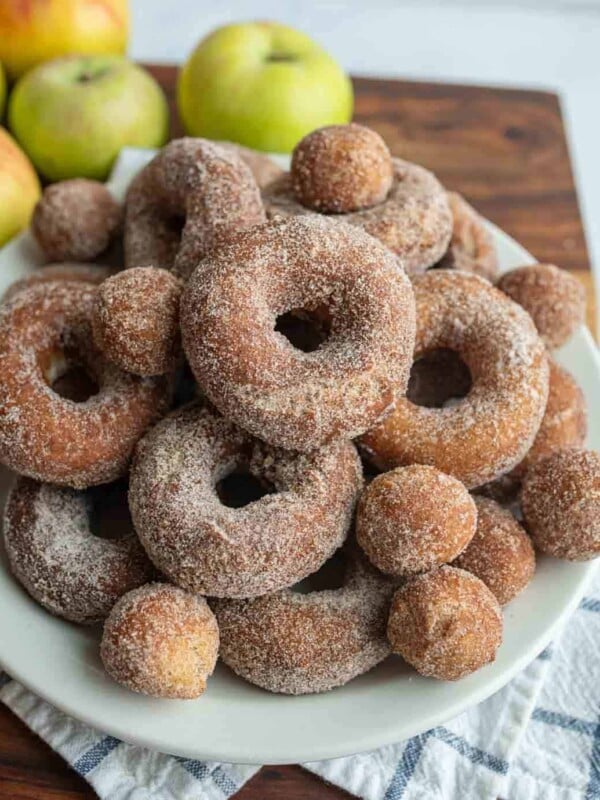 apple cider donuts and holes dusted with sugar on a white plate