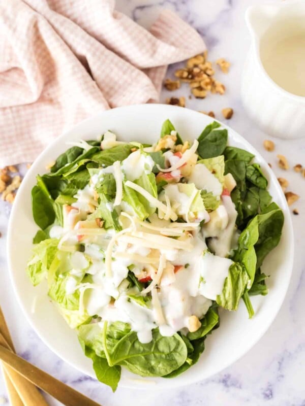 white dish with apple salad served with cheese and creamy dressing.