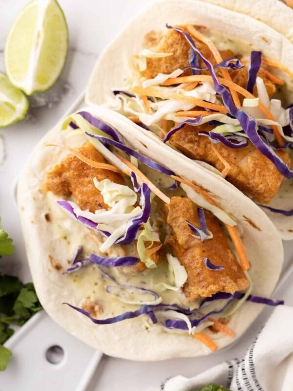 deep fried baja fish taco recipe with cabbage on a flour tortilla with limes.