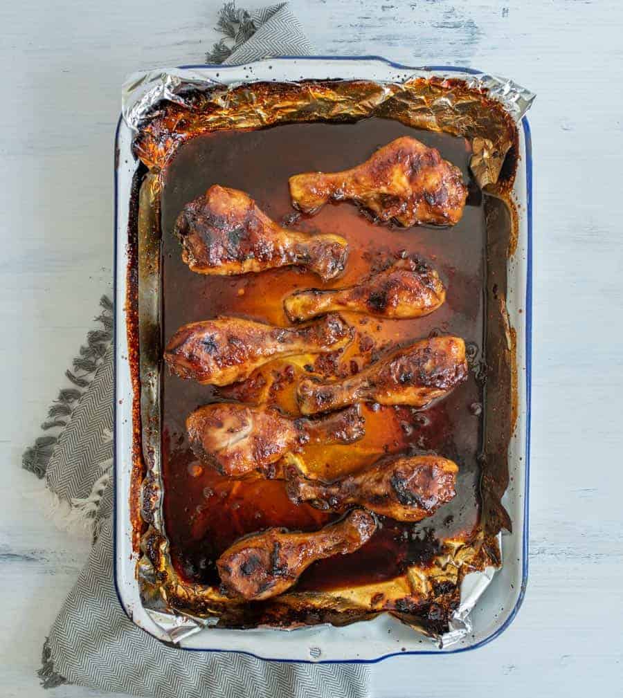 pan with chicken legs in it with lots of sauce on the bottom of the pan.