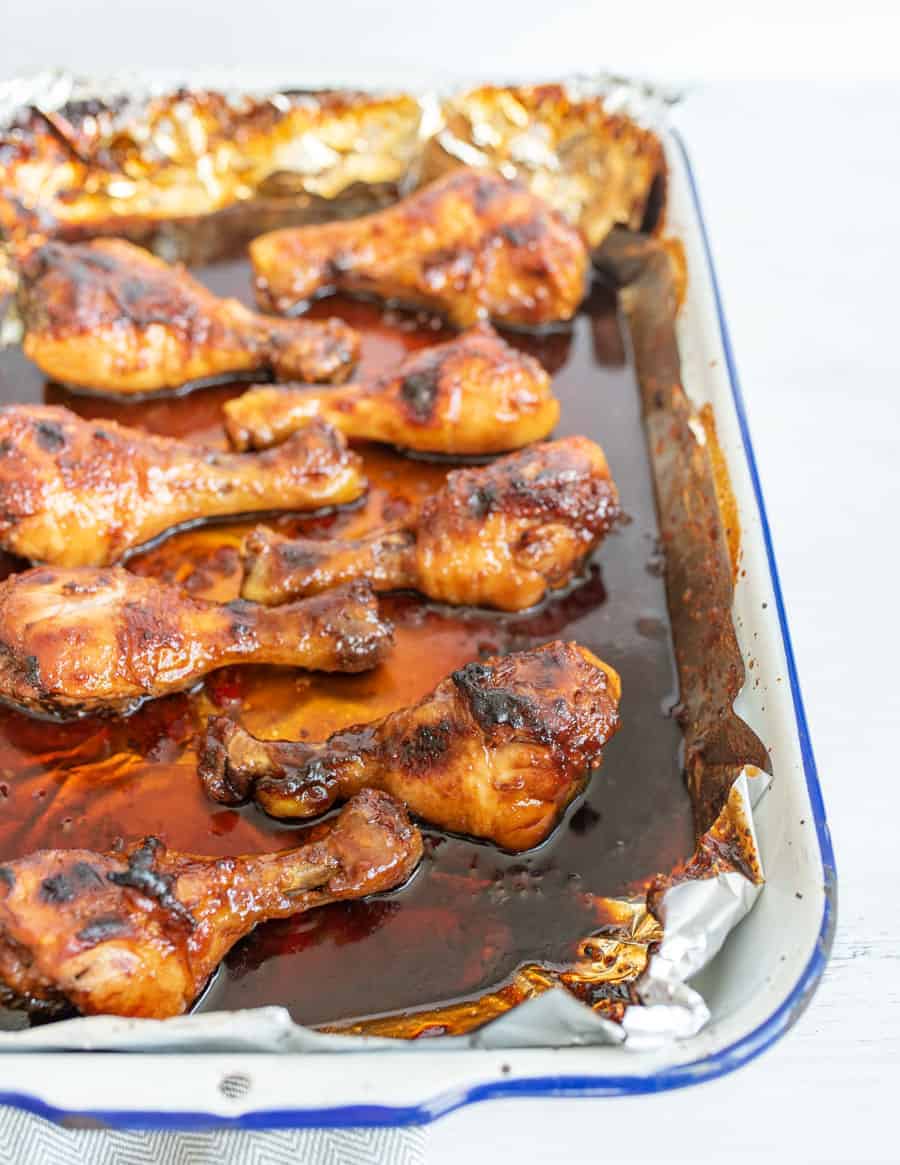 side view of multiple chicken drumsticks in the pan they cooked in.