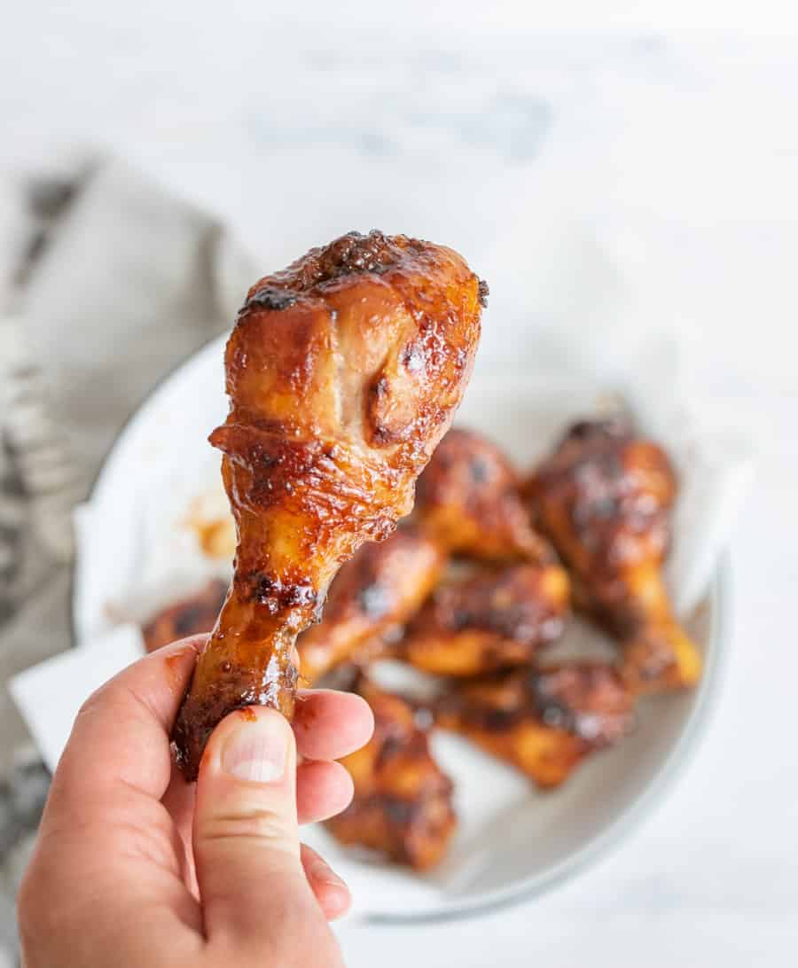 POV hand holding sticky saucy chicken leg.