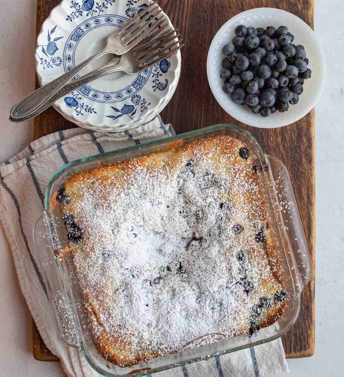 whole blueberry cobbler in a clear glass baking dish.