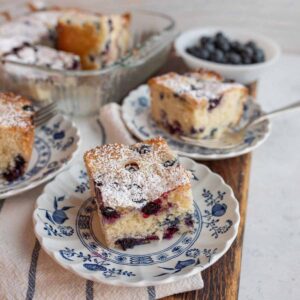 square serving of blueberry cobbler recipe on delicate blue china.