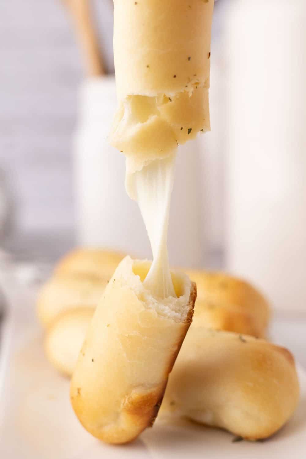 stringy cheesy bosco sticks ripped in half being stretched in half.