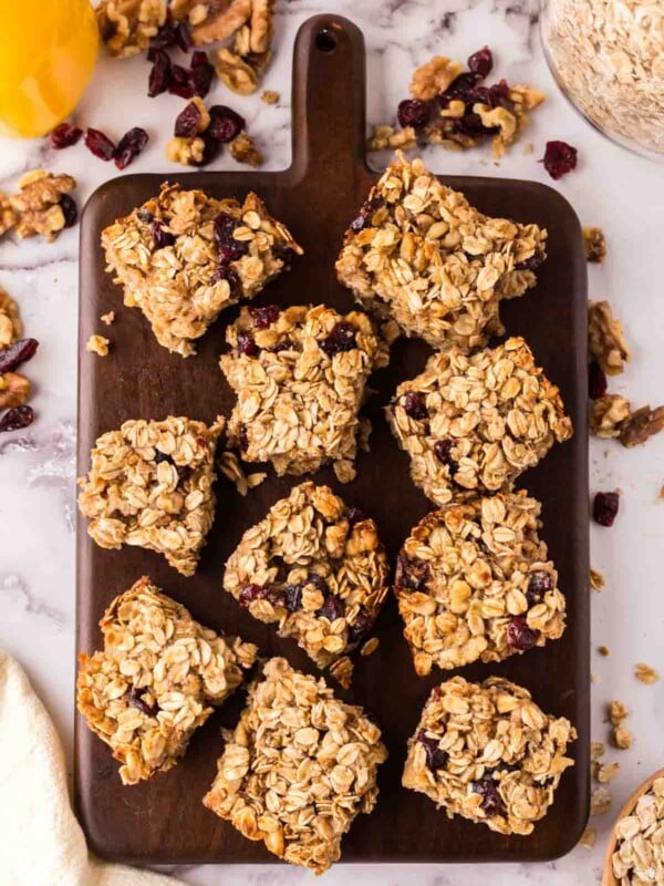 oat breakfast bars cut into square servings on a wooden board.