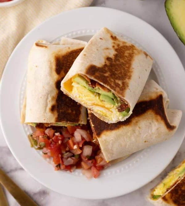 grilled and cut in half stack of breakfast burritos on a white plate.