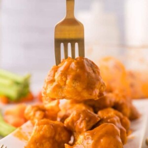 buffalo sauced cauliflower floret on a golden fork.