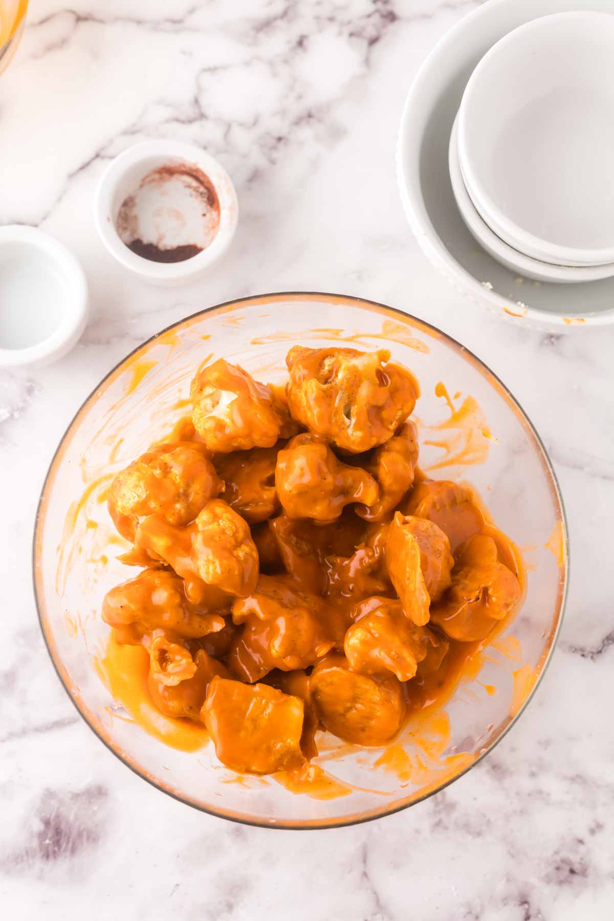 clear mixing bowl with buffalo cauliflower recipe.