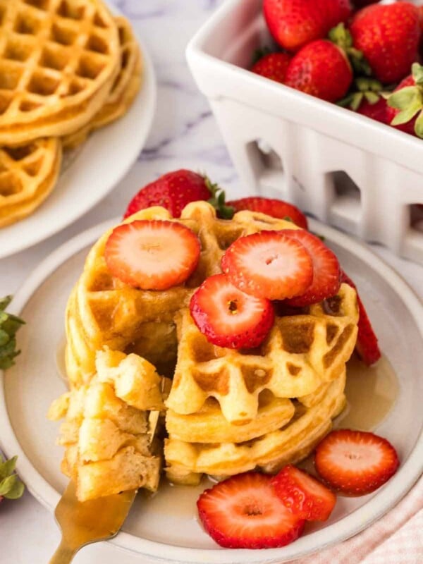 a stack of buttermilk waffles syrup and fresh strawberries