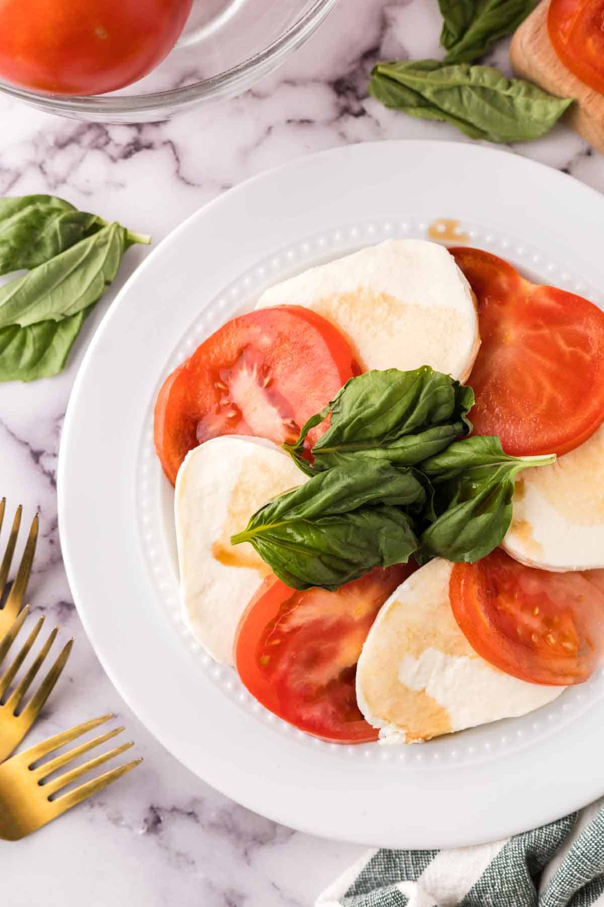 white plate with tomato basil and mozzarella for the caprese salad recipe.