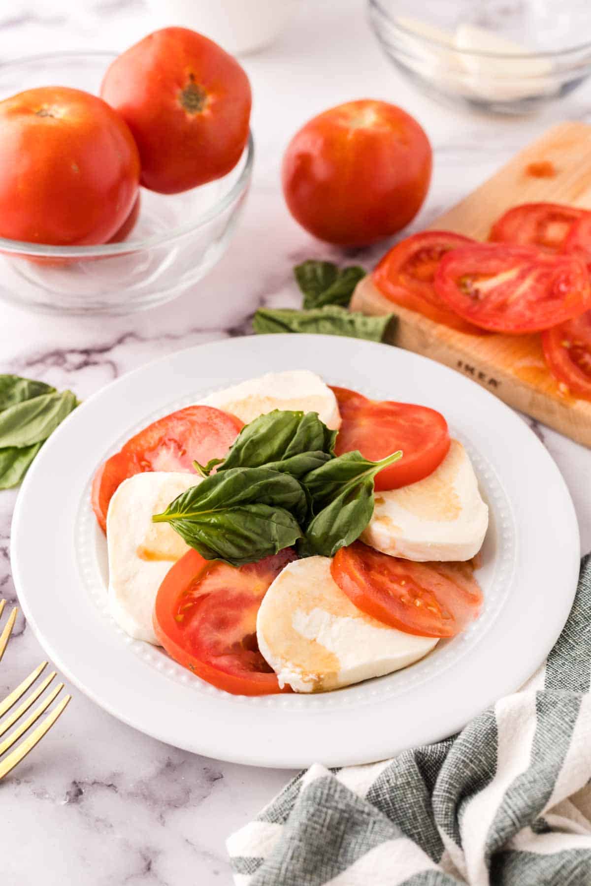 white plate with tomato basil and mozzarella for the caprese salad recipe.