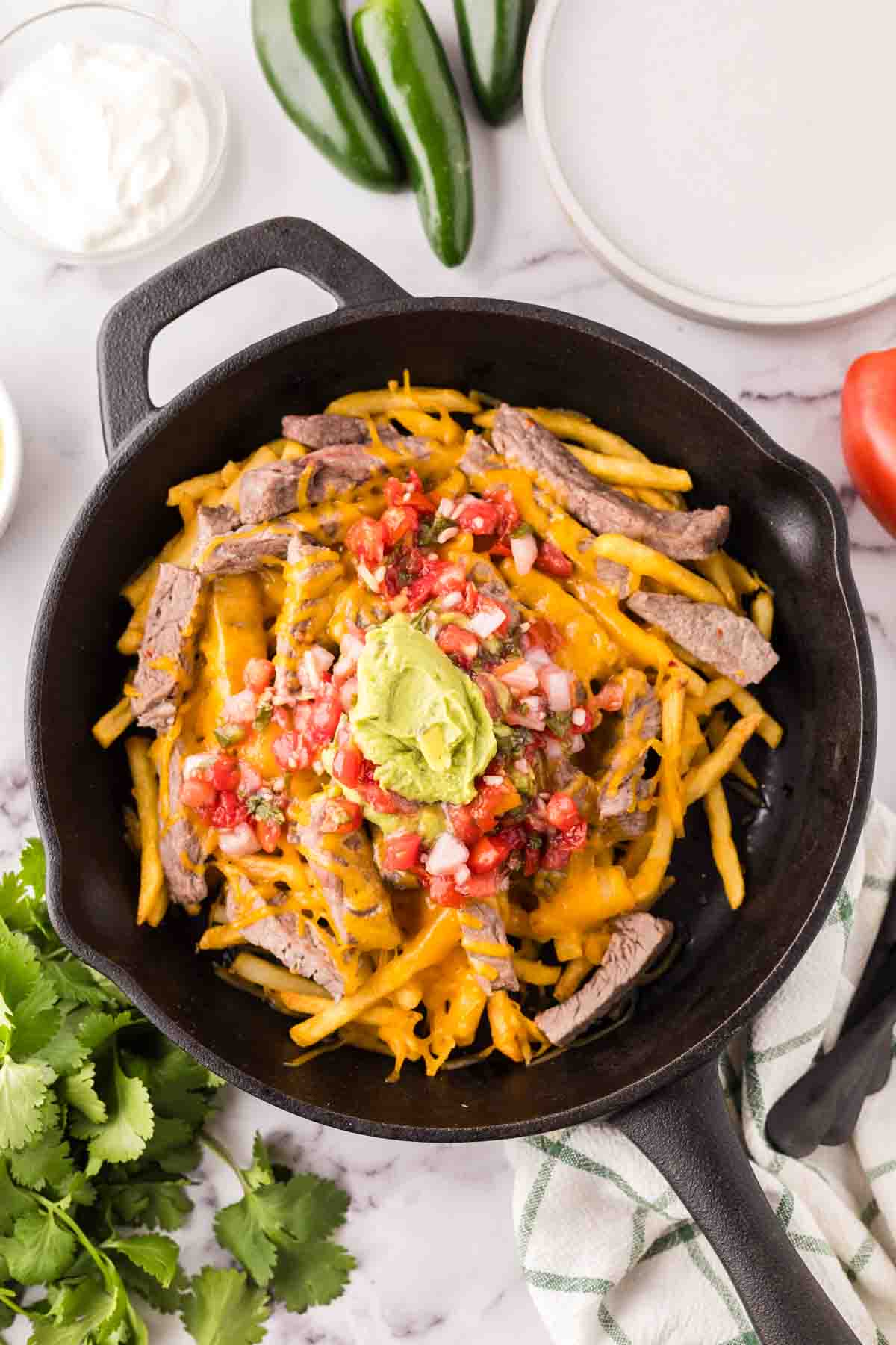 cast iron pan showing the progress of making carne asada fries recipe.