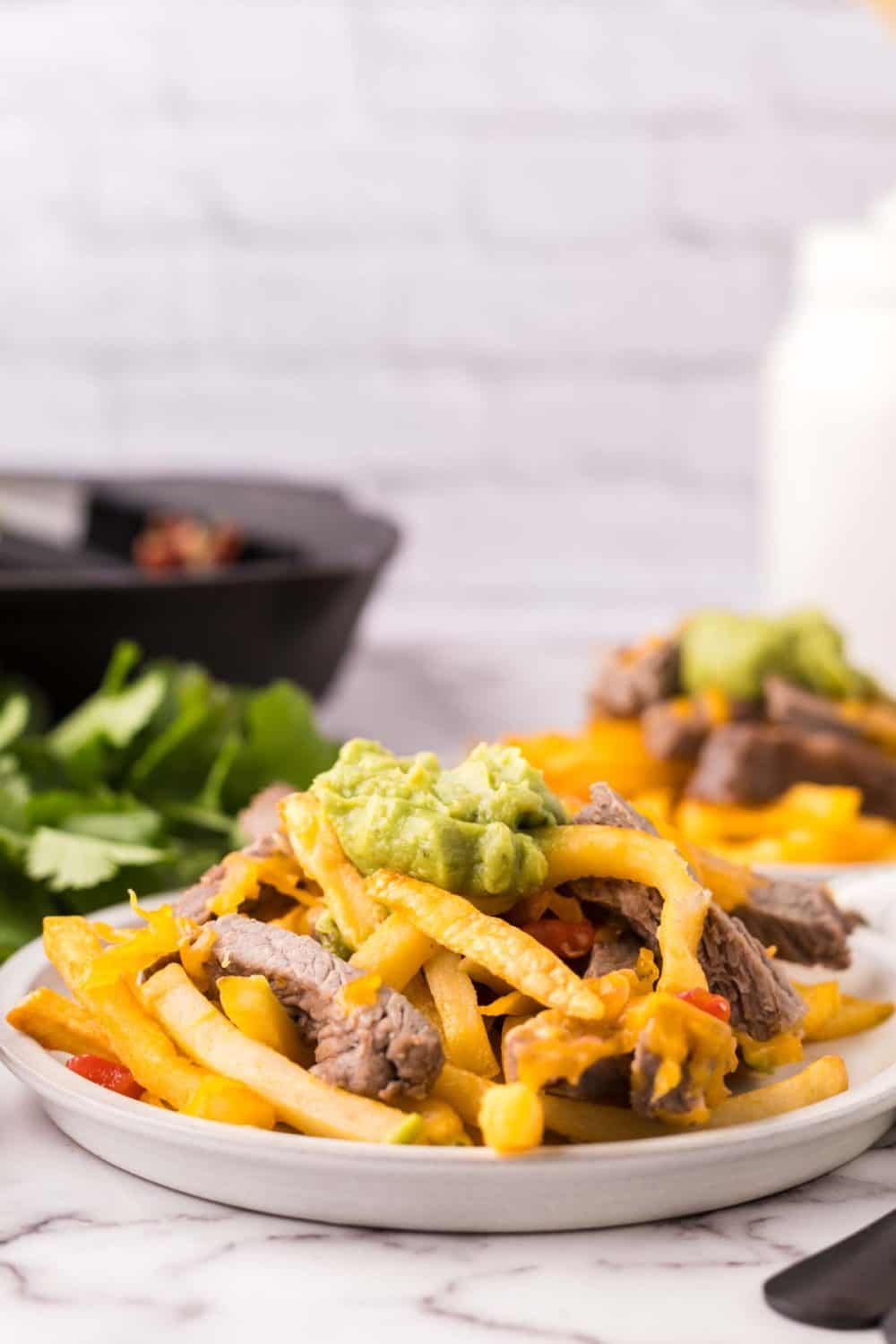 carne asada fries on round white plates.