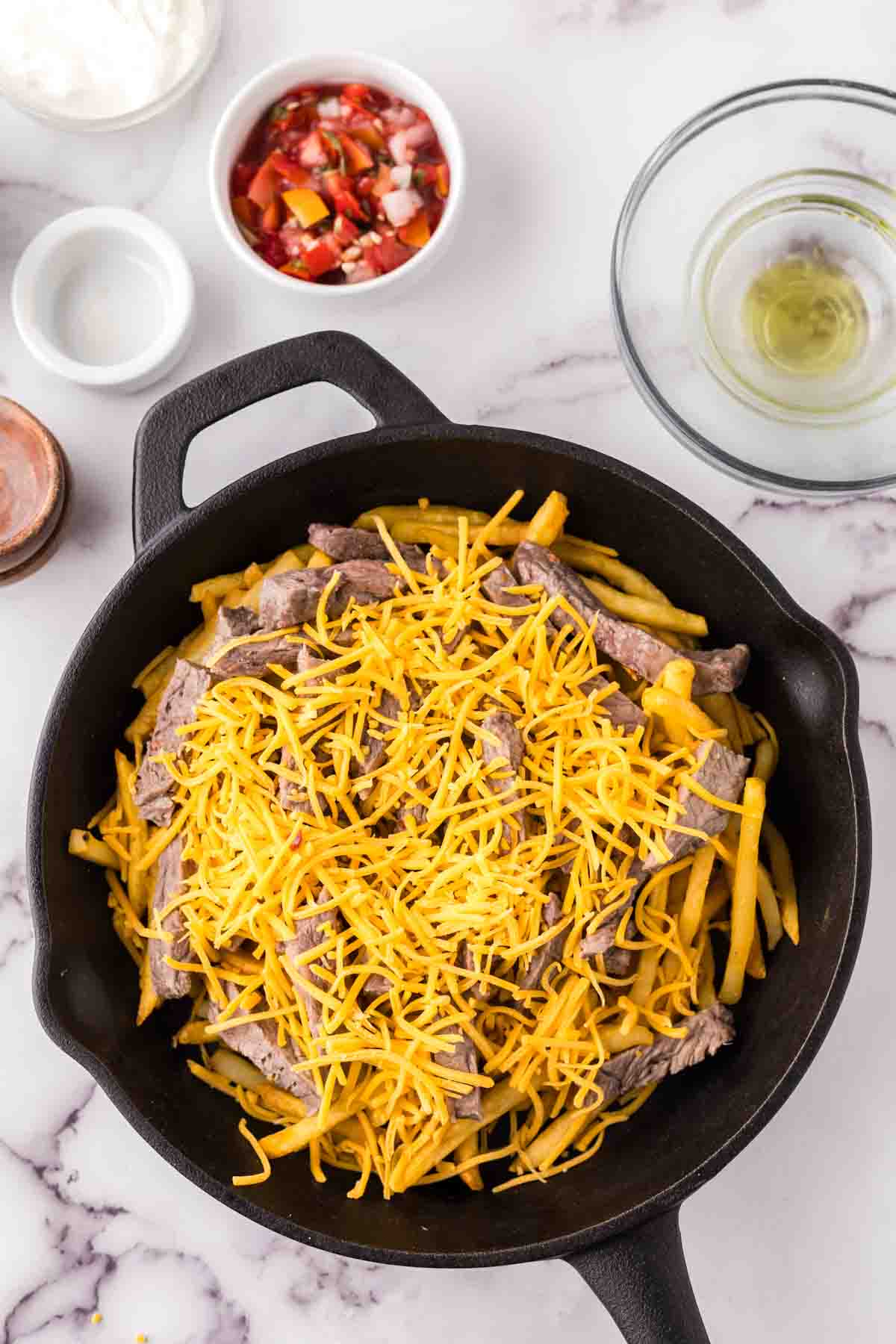 cast iron pan showing the progress of making carne asada fries recipe.