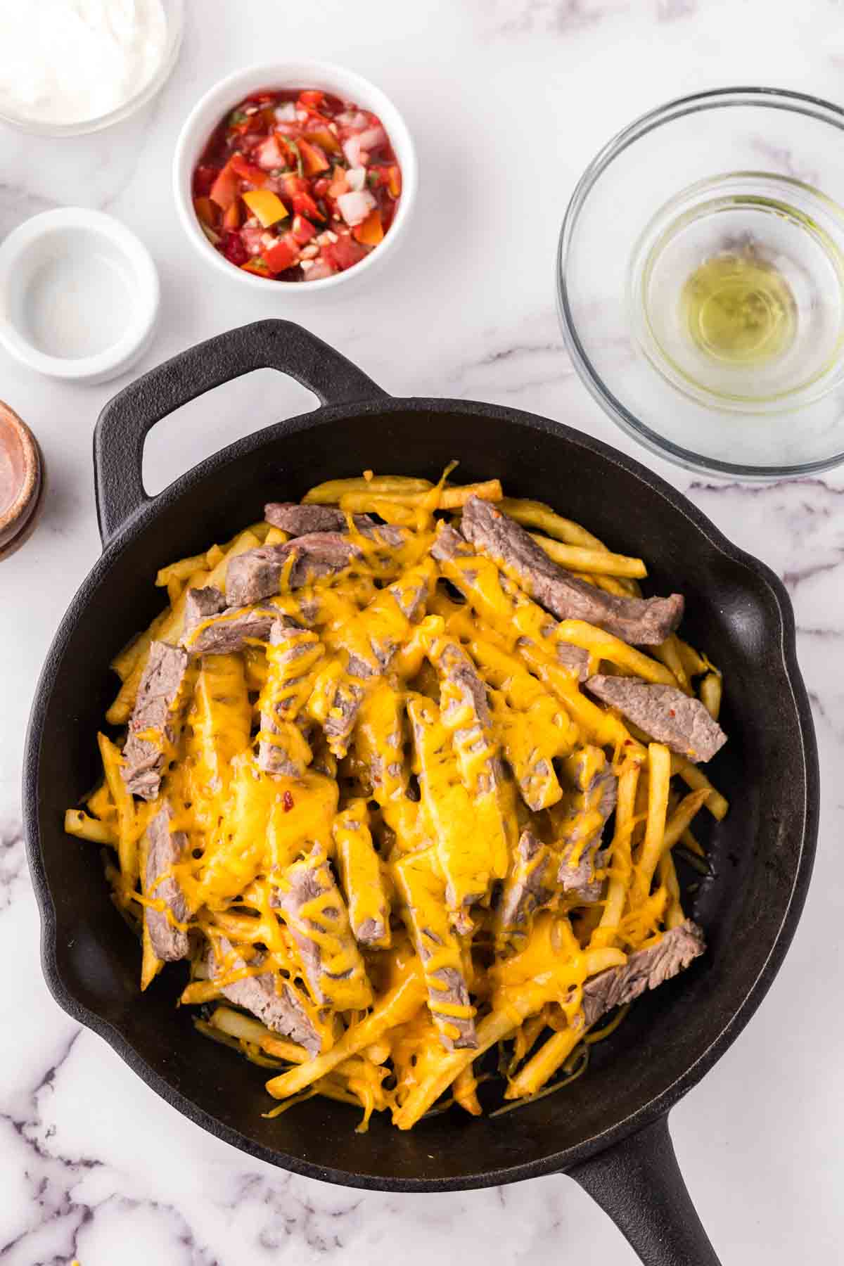 cast iron pan showing the progress of making carne asada fries recipe.