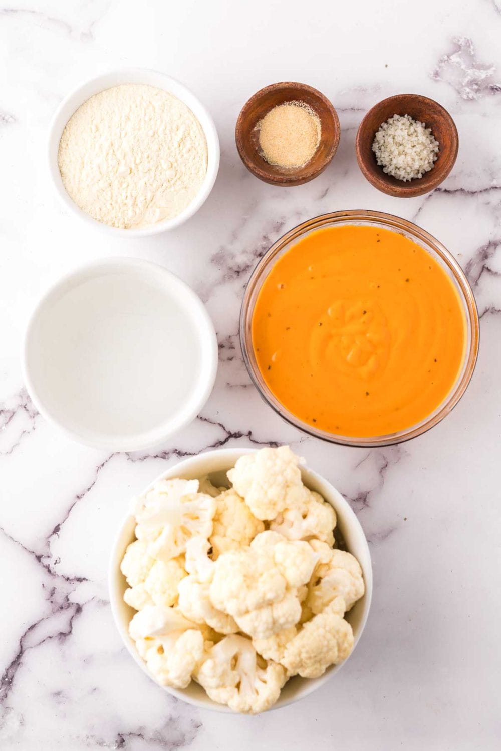 portion bowls each with raw ingredient to make cauliflower wings recipe.