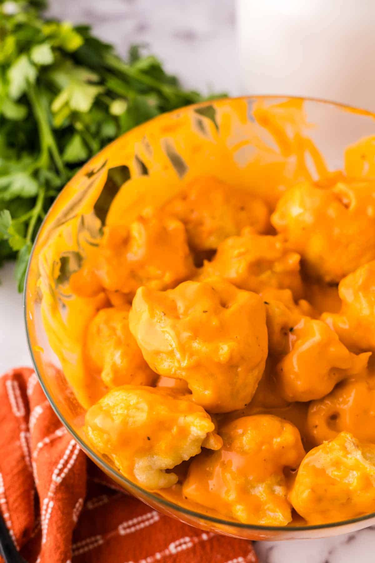 clear mixing bowl showing the progress of making cauliflower wings recipe.