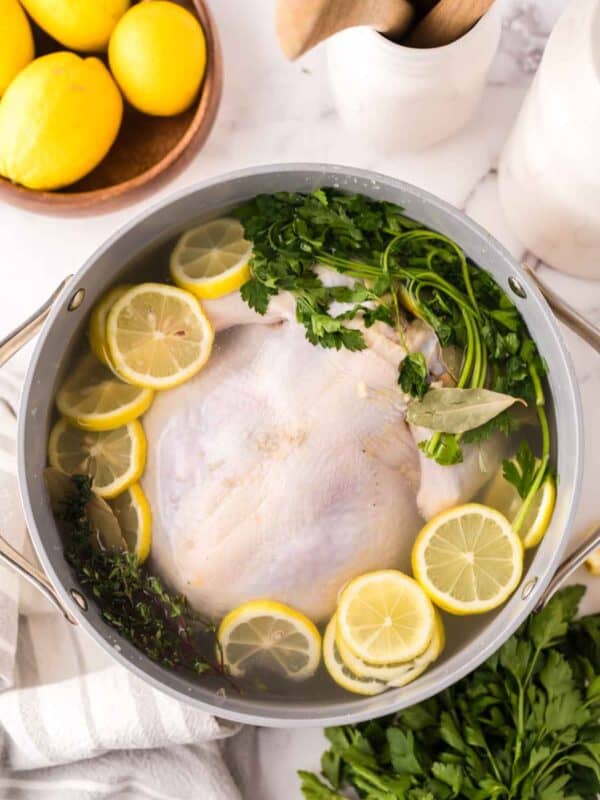 whole chicken in a large stock pot brining in sliced lemon and herbs.