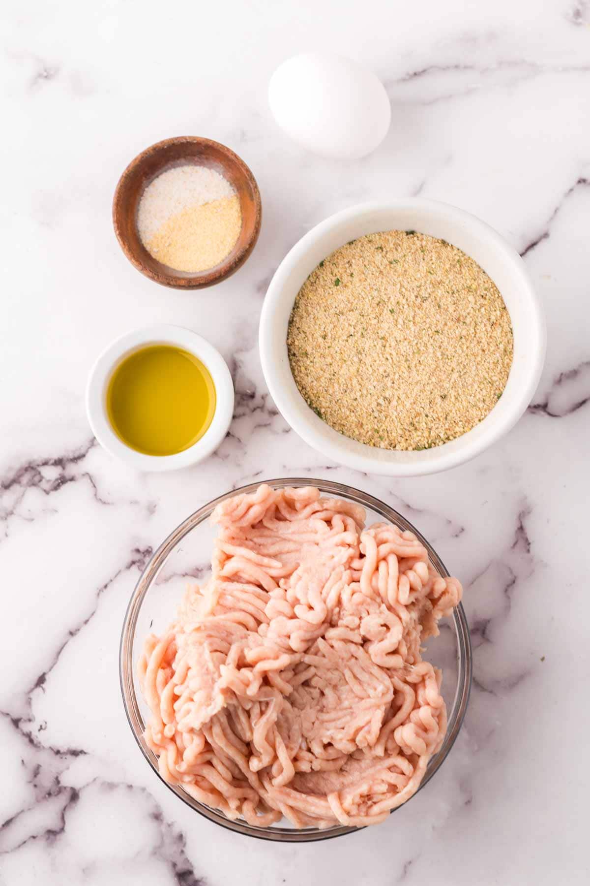 portion bowls each with raw ingredient to make chicken meatballs.