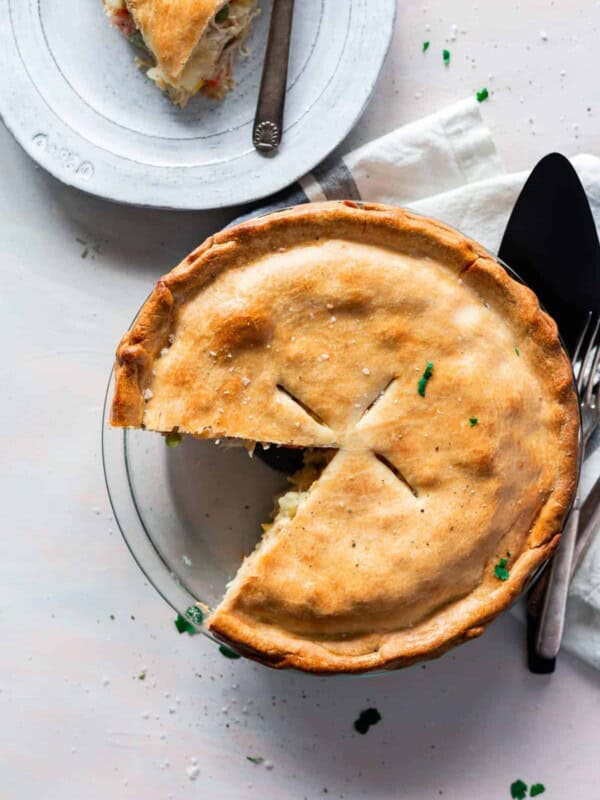 top view chicken pot pie in a clear pie pan with a golden crust and once slice taken out