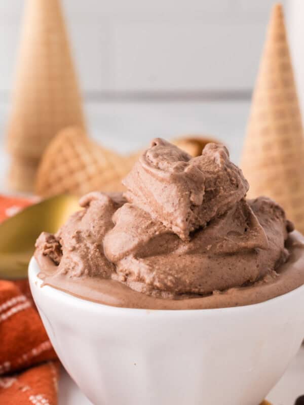 chocolate peanut butter ice cream scooped in a bowl with cones and a golden spoons around.