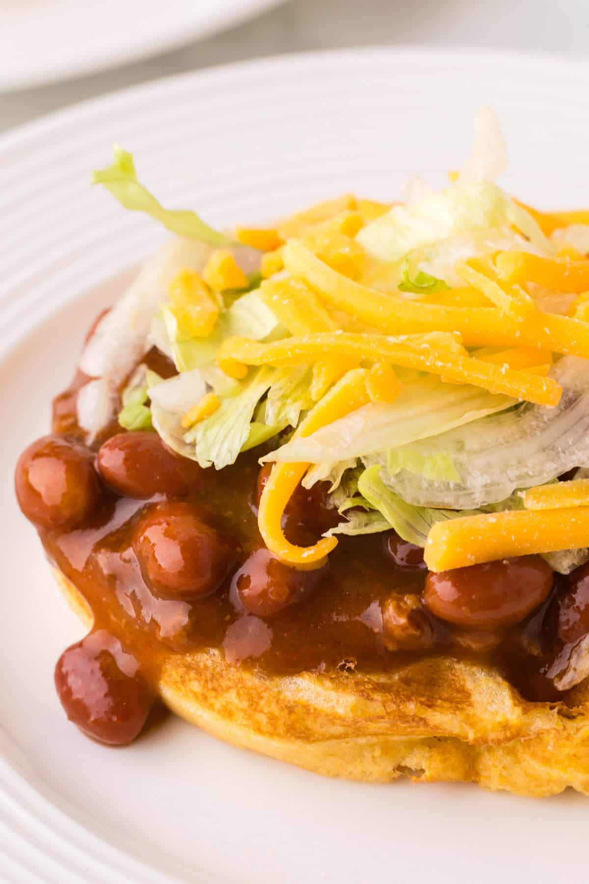 round white plate with cornbread waffles and chili.