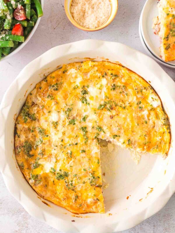 top view of a whole crustless quiche in the baking dish with one slice taken out