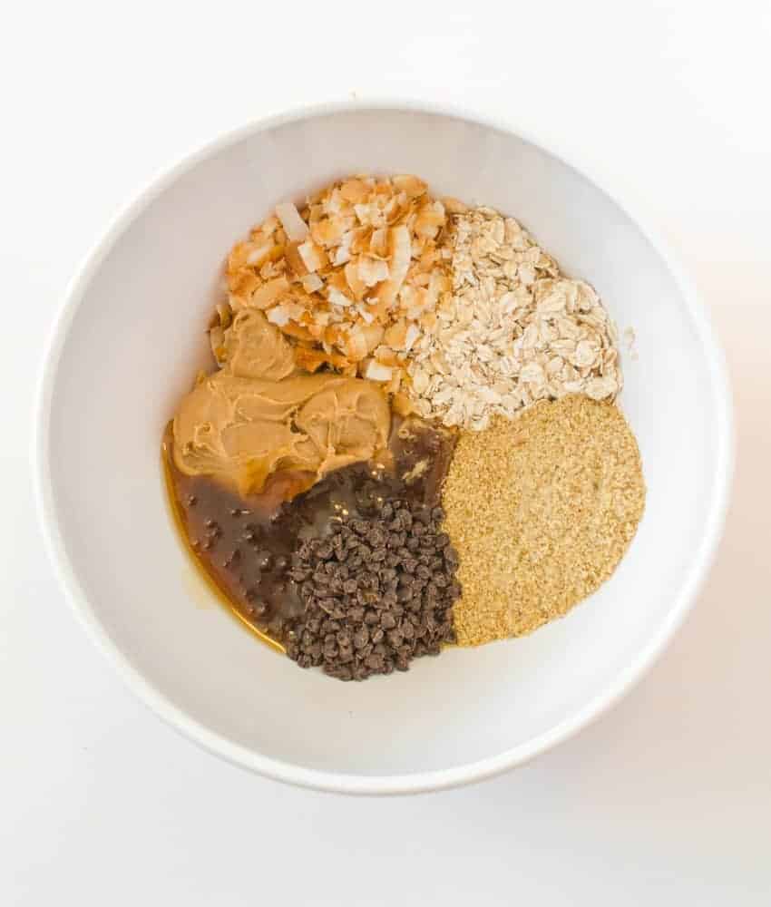 Ingredients for Peanut Butter Chocolate Chip Oatmeal Energy Balls including dry oats, peanut butter, honey, toasted coconut flakes, ground flaxseed, and mini chocolate chips.