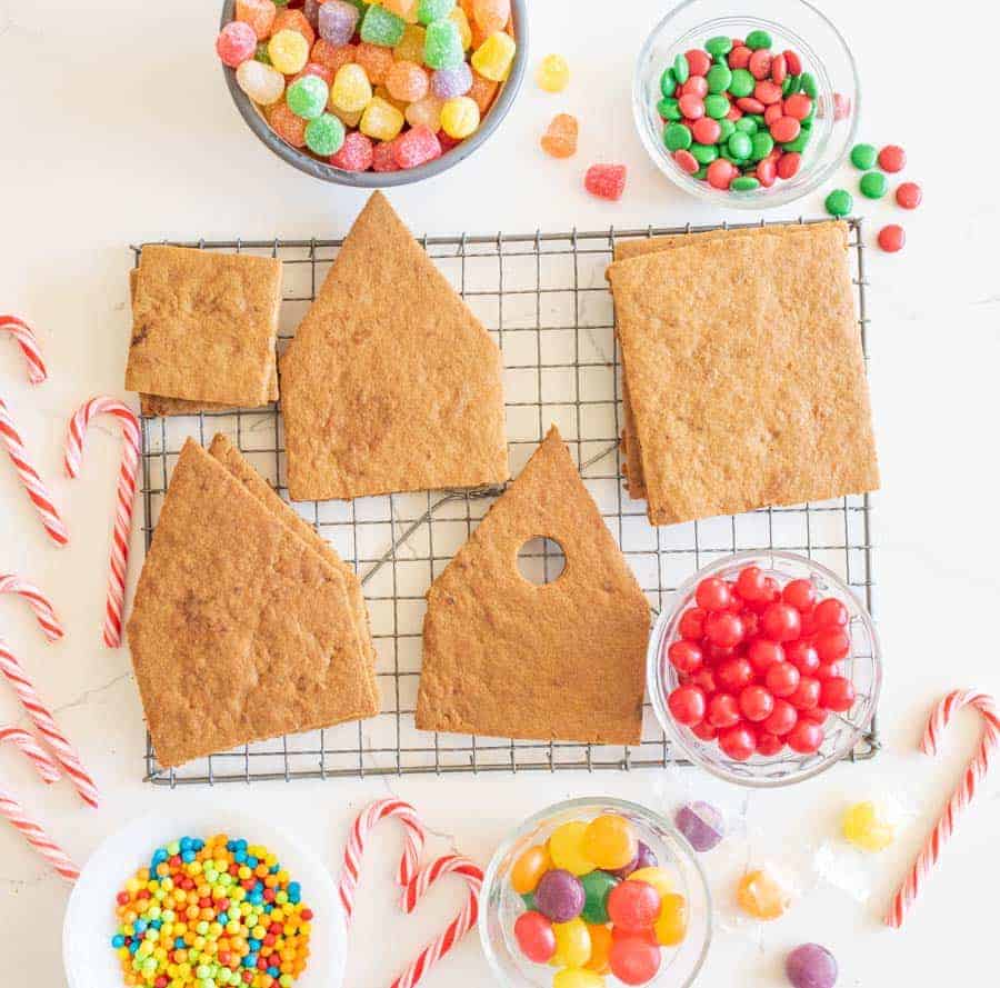 ascetic image of ginger bread house ingredients before construction - cookie pieces in house shape on wire rack and candies all around