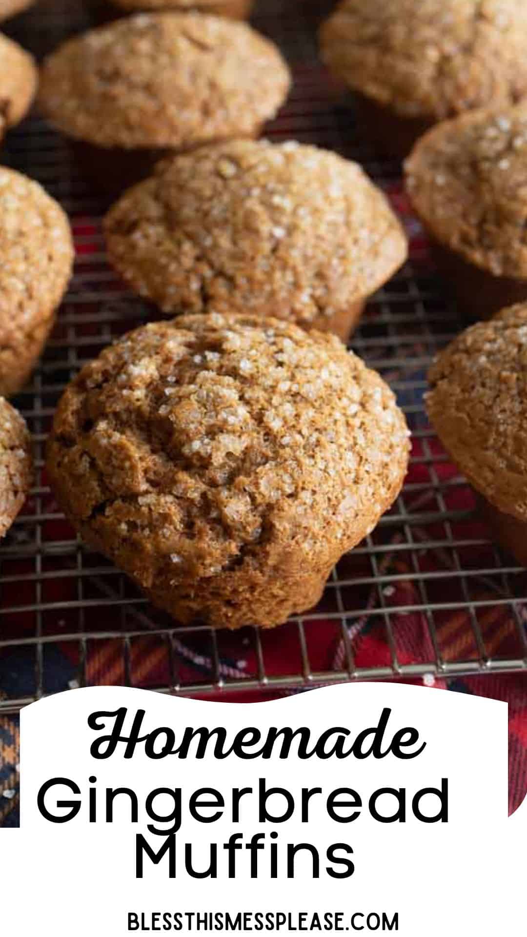 Close-up of homemade gingerbread muffins on a cooling rack, displayed on a colorful cloth. The muffins have a textured top with sugar sprinkled on them. Text at the bottom reads Homemade Gingerbread Muffins and blessthismessplease.com.