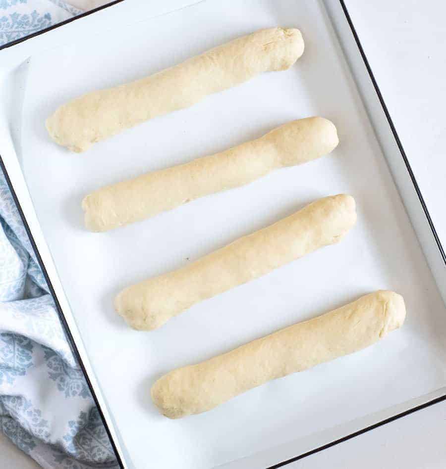 four long rolls of dough in a white pan.