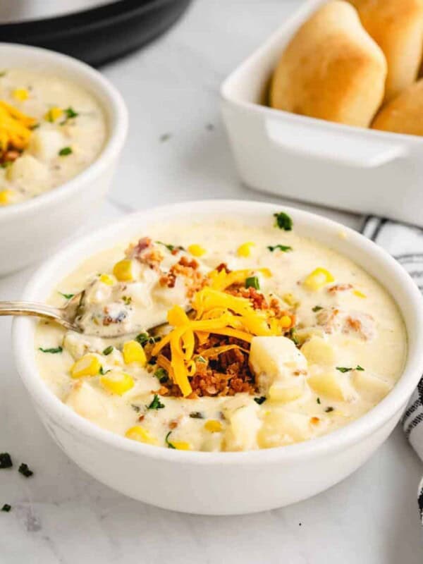 creamy potato soup with an instant pot in the background and garnished with cheddar cheese and greens