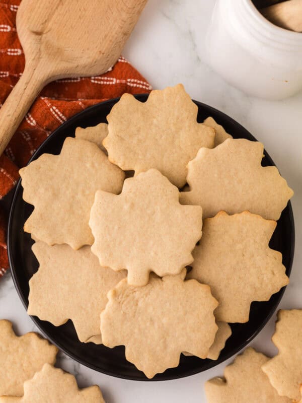 maple leaf shaped maple sugar cookies on a round black plate.