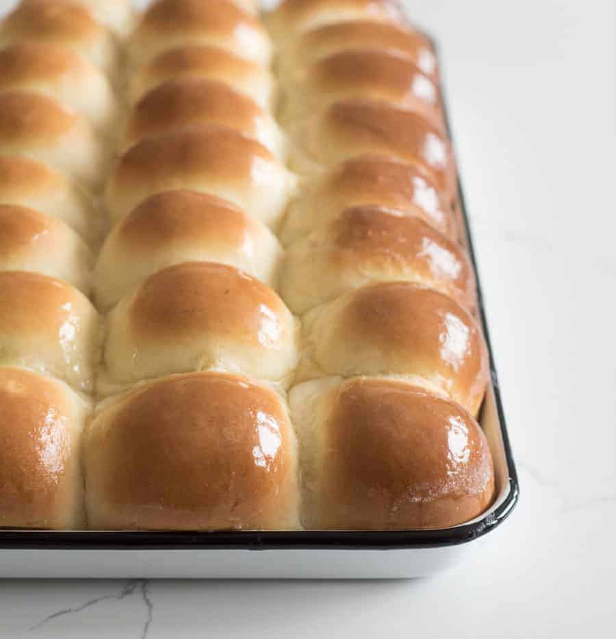 golden shiny dinner rolls hot out of the oven still in the pan with butter on top.