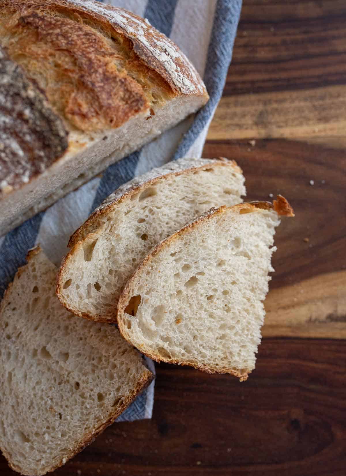 half loaf of sourdough bread with smaller slices on blue and white towel.