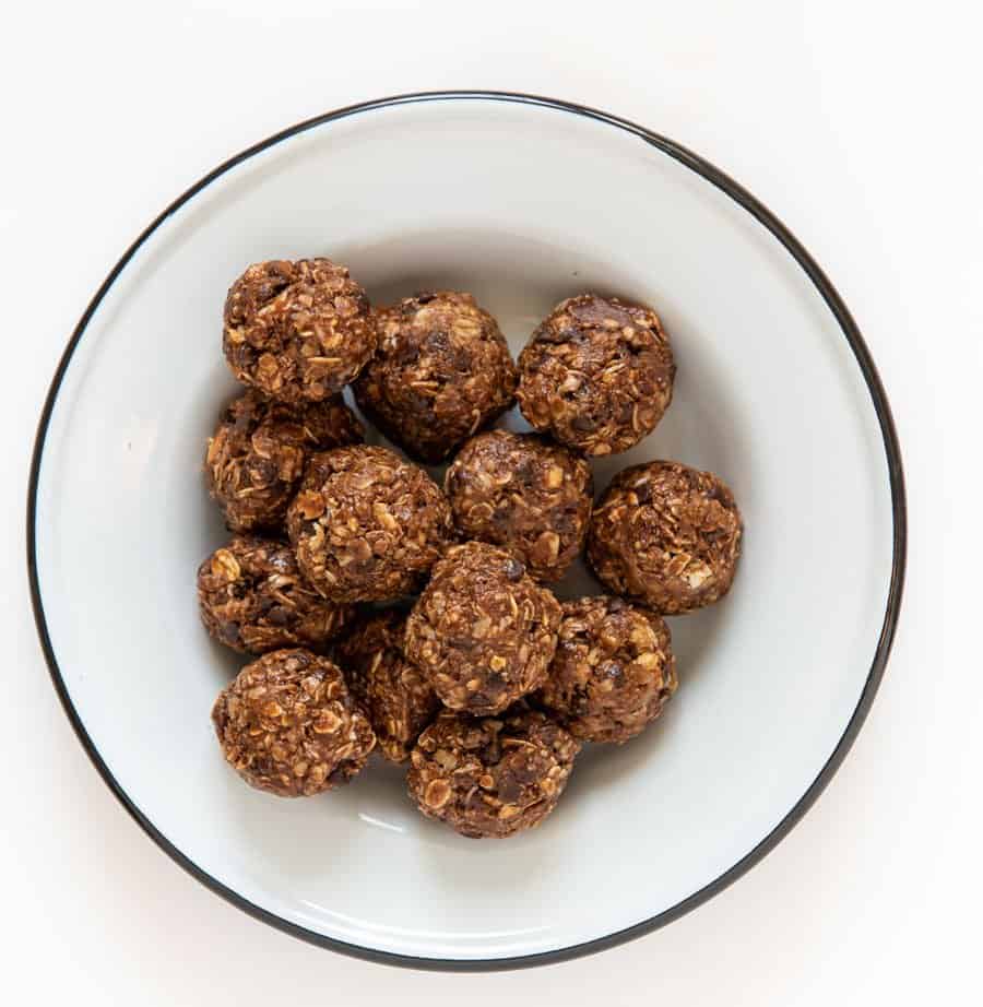 13 double chocolate oatmeal energy bites in a white enamel bowl with a black rim.