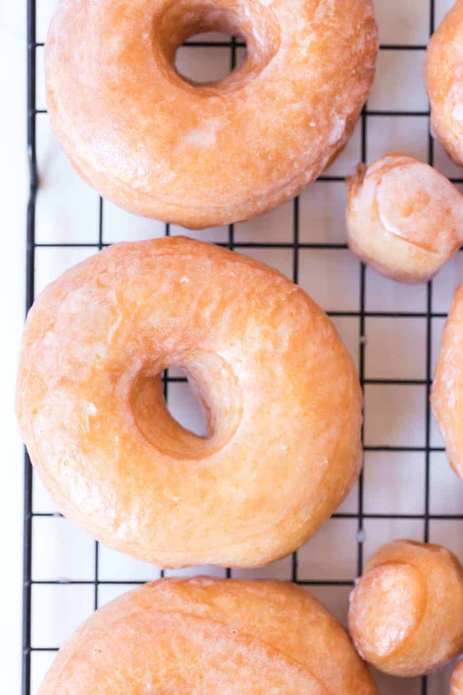 top view of some old fashioned glazed doughnuts and doughnut holes on a cooling rack.