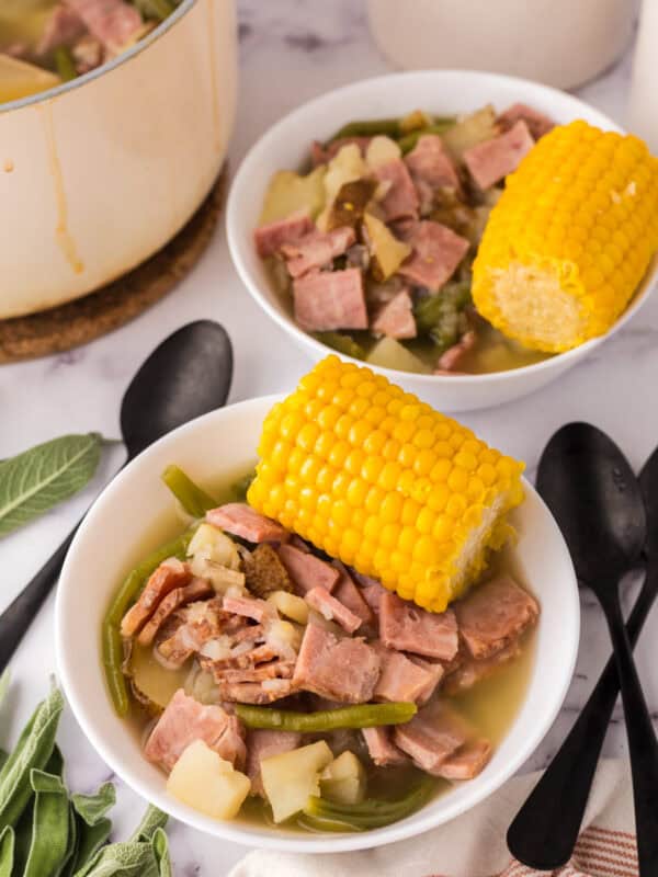 One pot farmstead wonder recipe served in a white bowl with corn on top next to black spoons.