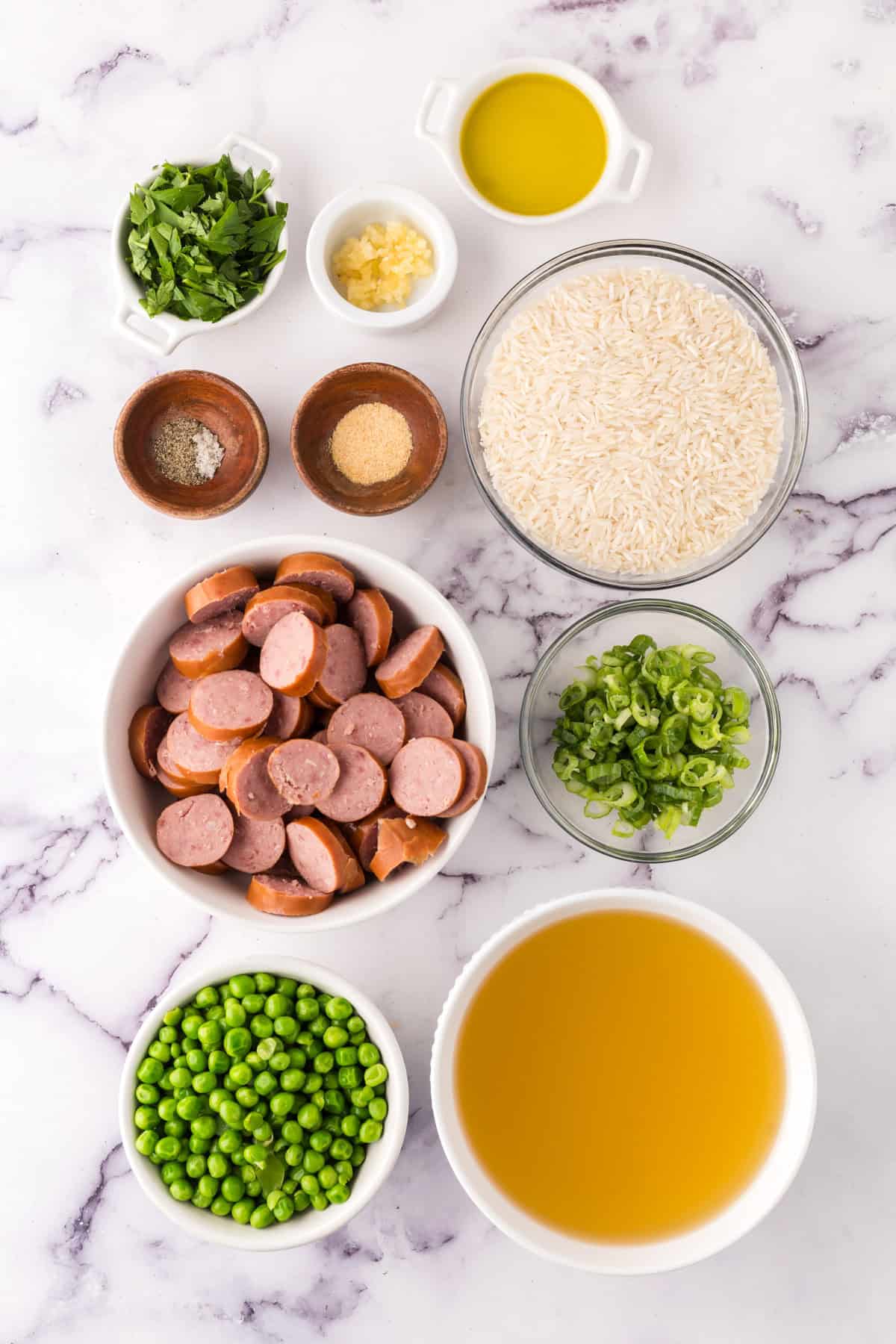 portion bowls each with raw ingredients to make one pot sausage peas and rice recipe.