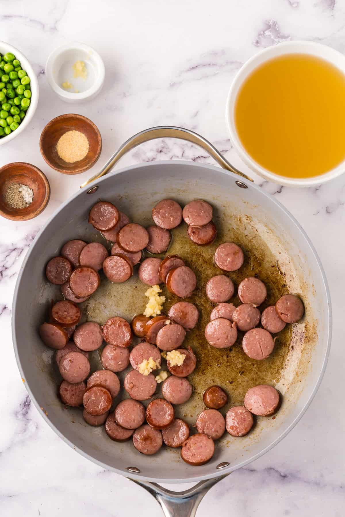 one pot sausage peas and rice in a pan in the progress of cooking.