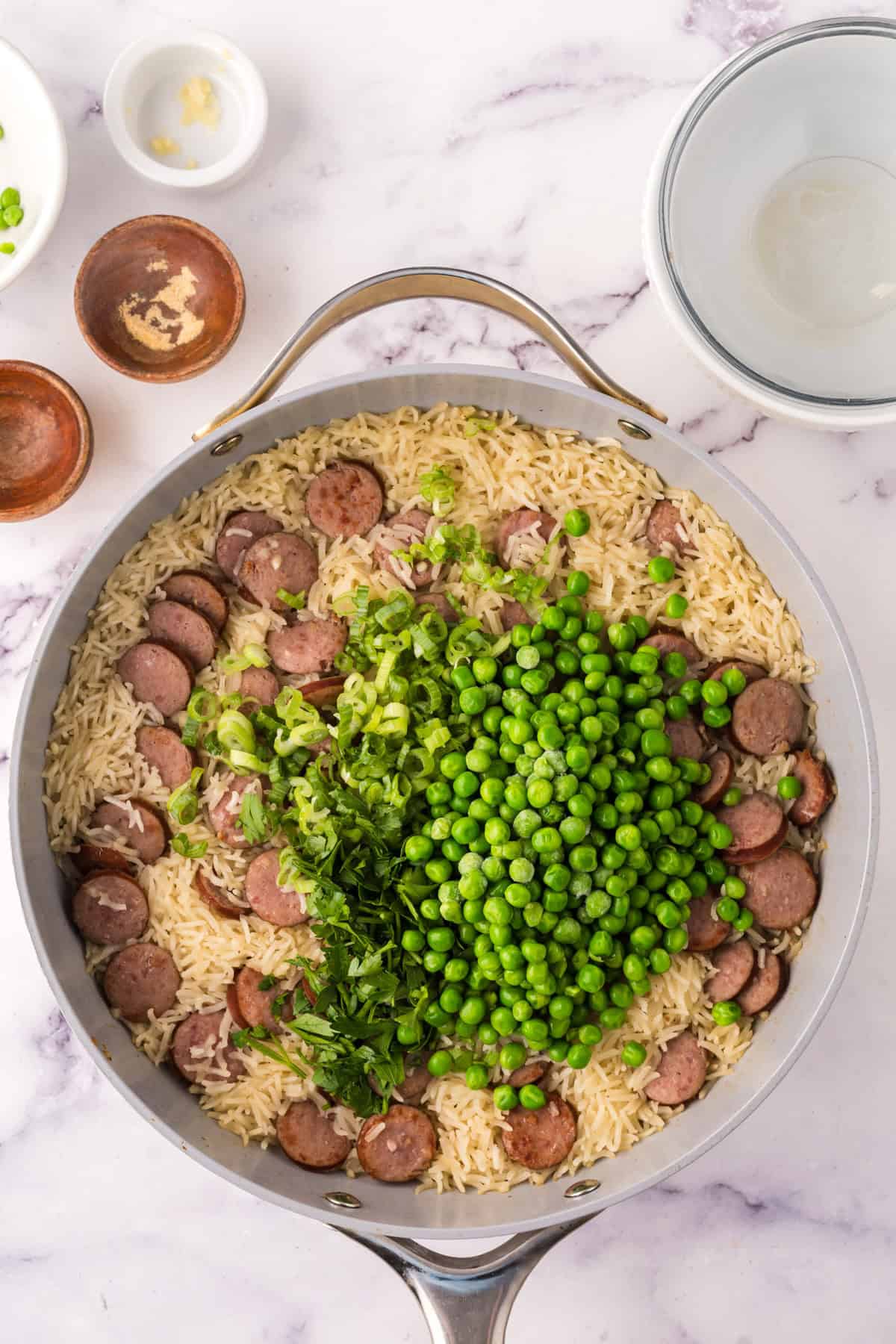 one pot sausage peas and rice in a pan in the progress of cooking.