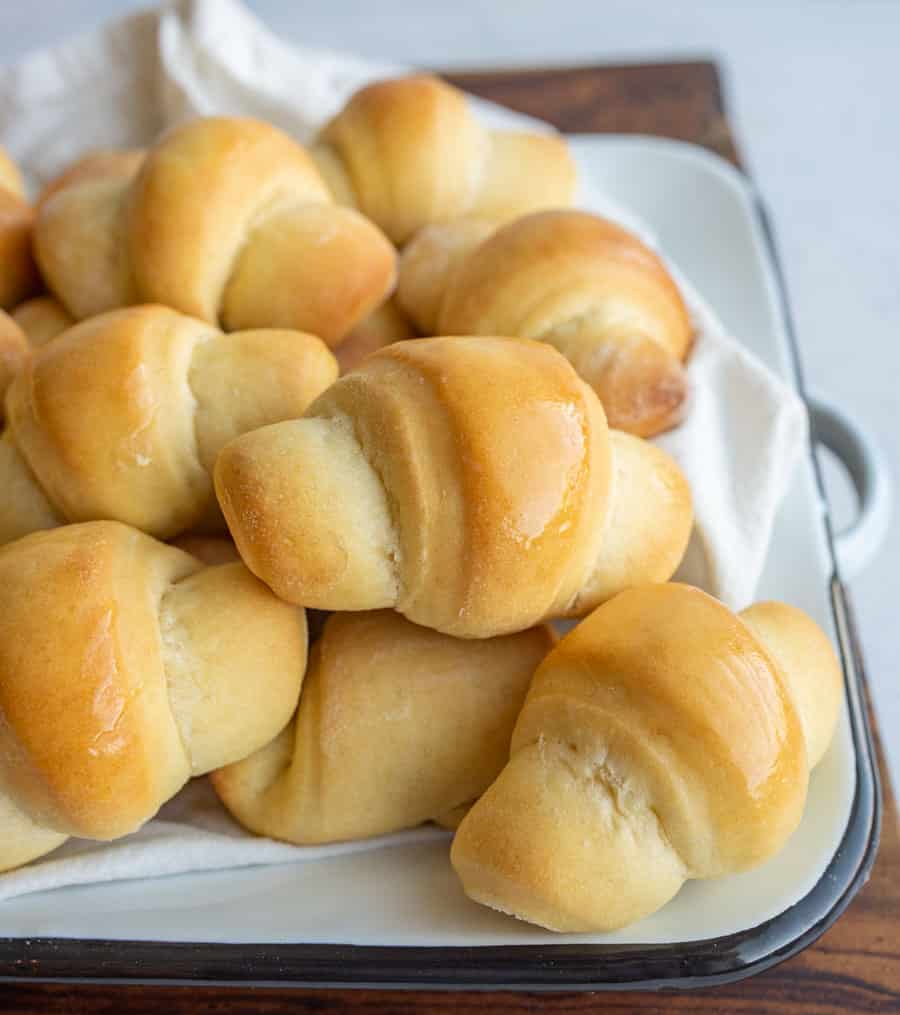 small shiny buttered rolls in a rolled up croissant shape