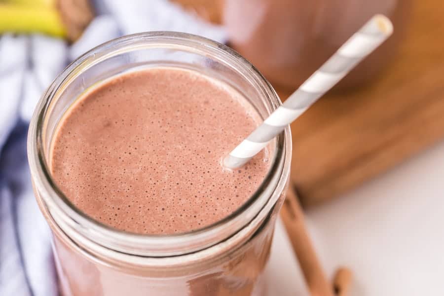 closeup of healthy peanut butter chocolate smoothie with gray striped paper straw