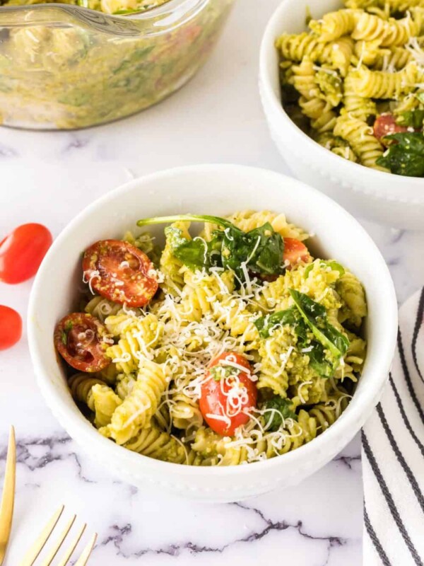 portion bowl of pesto pasta salad with shredded parmesan cheese